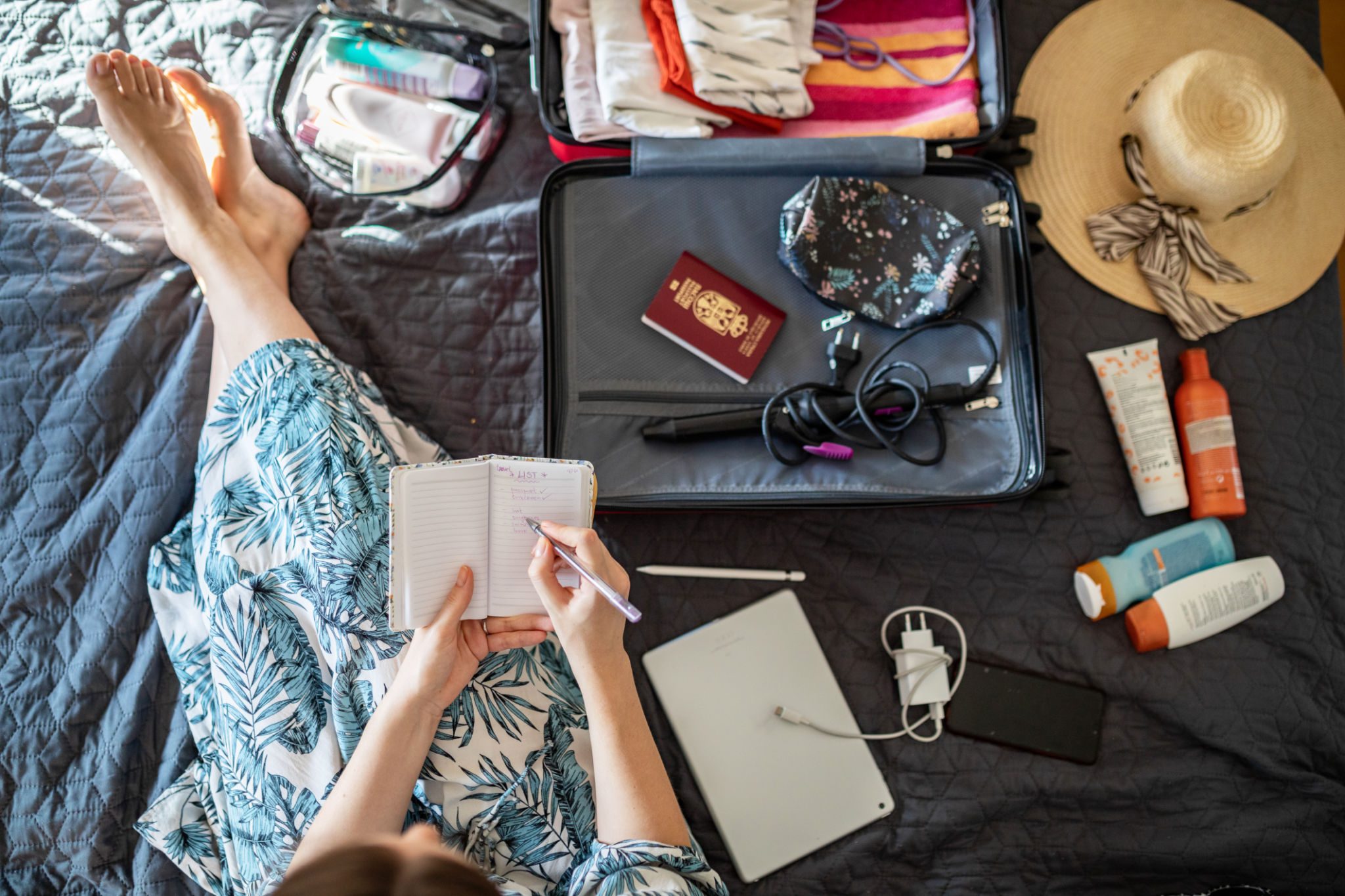 Woman preparing travel essentials on bed