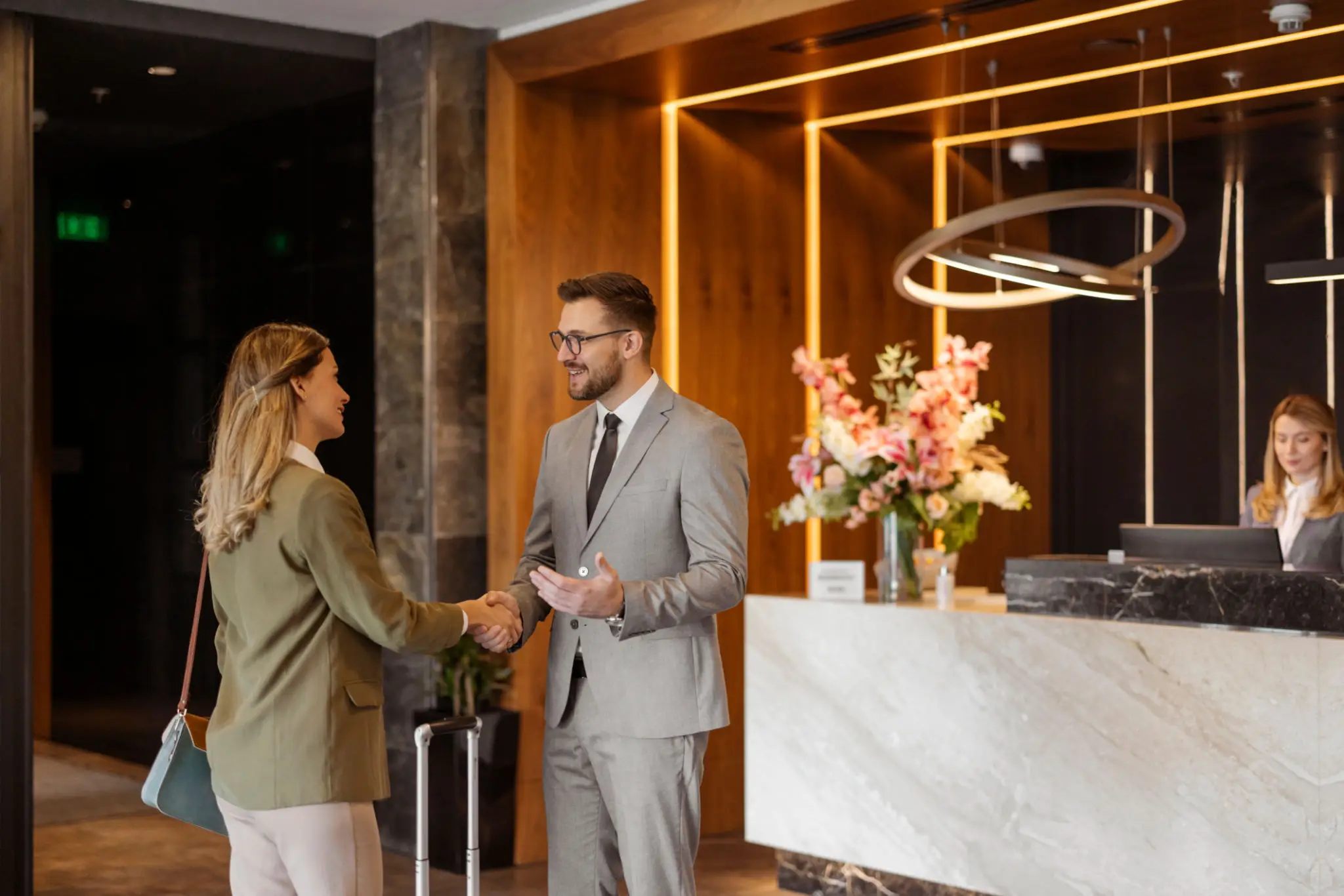Two professionals shaking hands in a modern office lobby.