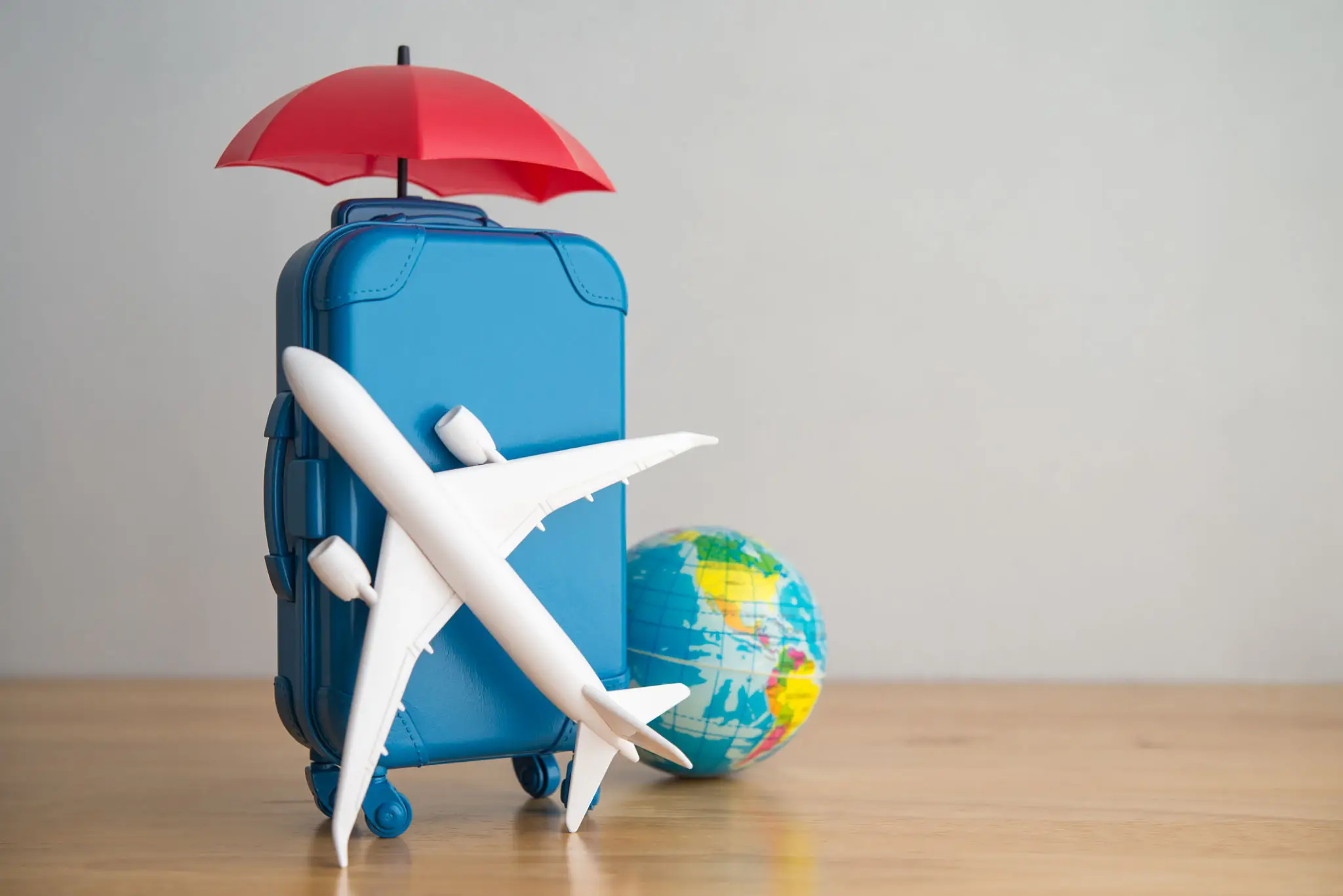 Travel essentials including a suitcase, globe, umbrella, and airplane model.
